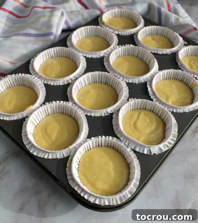 smooth yellow cupcake batter neatly piped into cupcake liners, ready for baking.