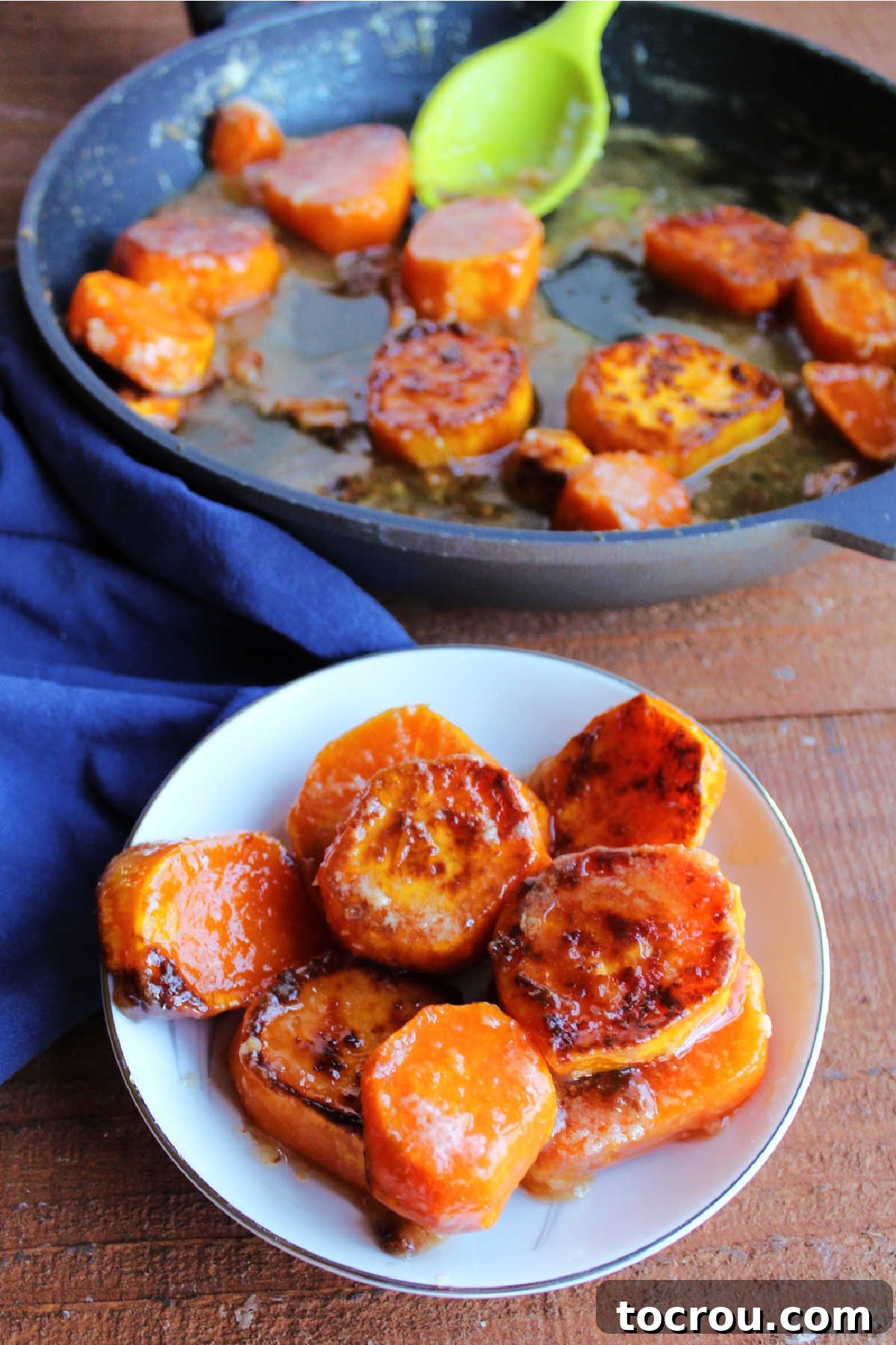 A small serving bowl filled with beautifully caramelized candied skillet sweet potatoes, with the large skillet blurred in the background, ready for serving.