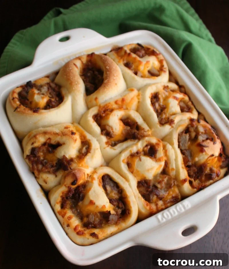 Cheesy BBQ Pulled Pork Buns Square baking dish filled with pulled pork buns that look kind of like cinnamon rolls but are stuffed with cheese and bbq pulled pork.