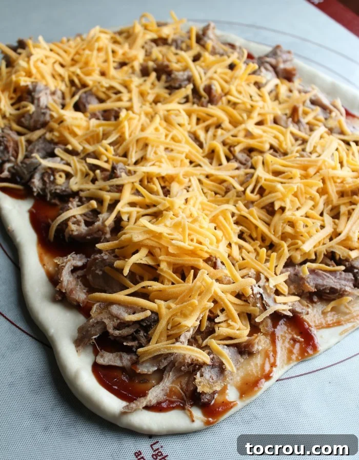 Dough with BBQ Pulled Pork and Cheese Rectangle of bread dough covered with bbq sauce, pulled pork and cheese.