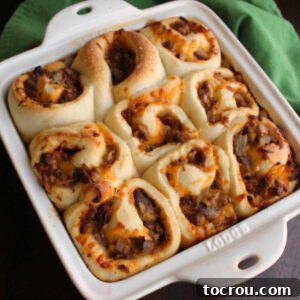 Square baking dish filled with pulled pork buns that look kind of like cinnamon rolls but are stuffed with cheese and bbq pulled pork.