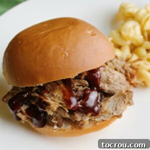 Instant Pot Root Beer Pulled Pork Recipe Card Image Pulled pork sandwich with bbq sauce on bun, featured in a recipe card.