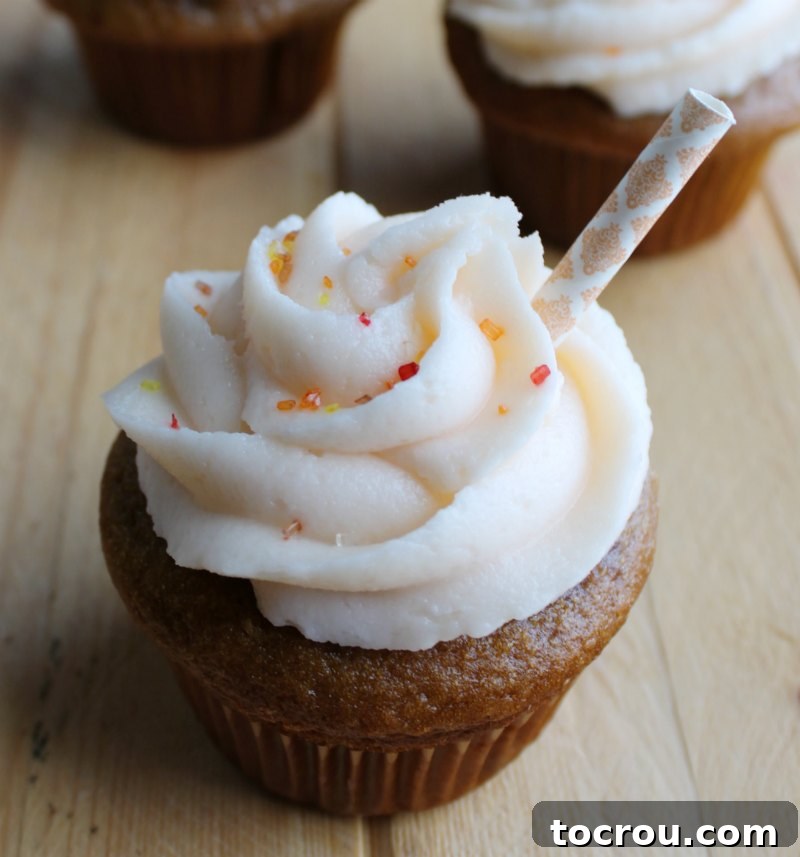 Close-up of a sweet tea cupcake adorned with a perfect swirl of peach frosting, beautifully decorated with a short paper straw, ready for serving.
