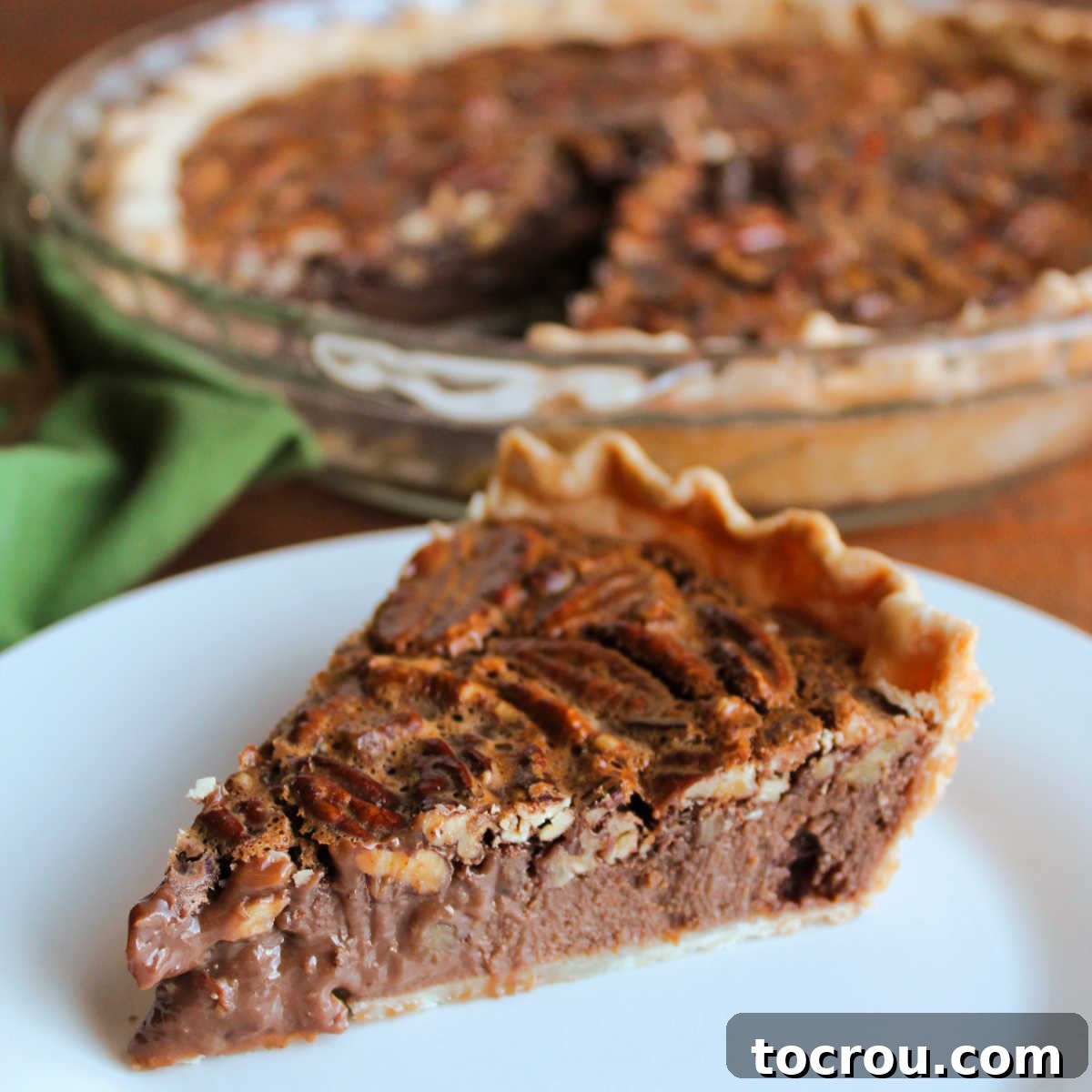 Piece of fudgy chocolate condensed milk pecan pie on plate, ready to eat.