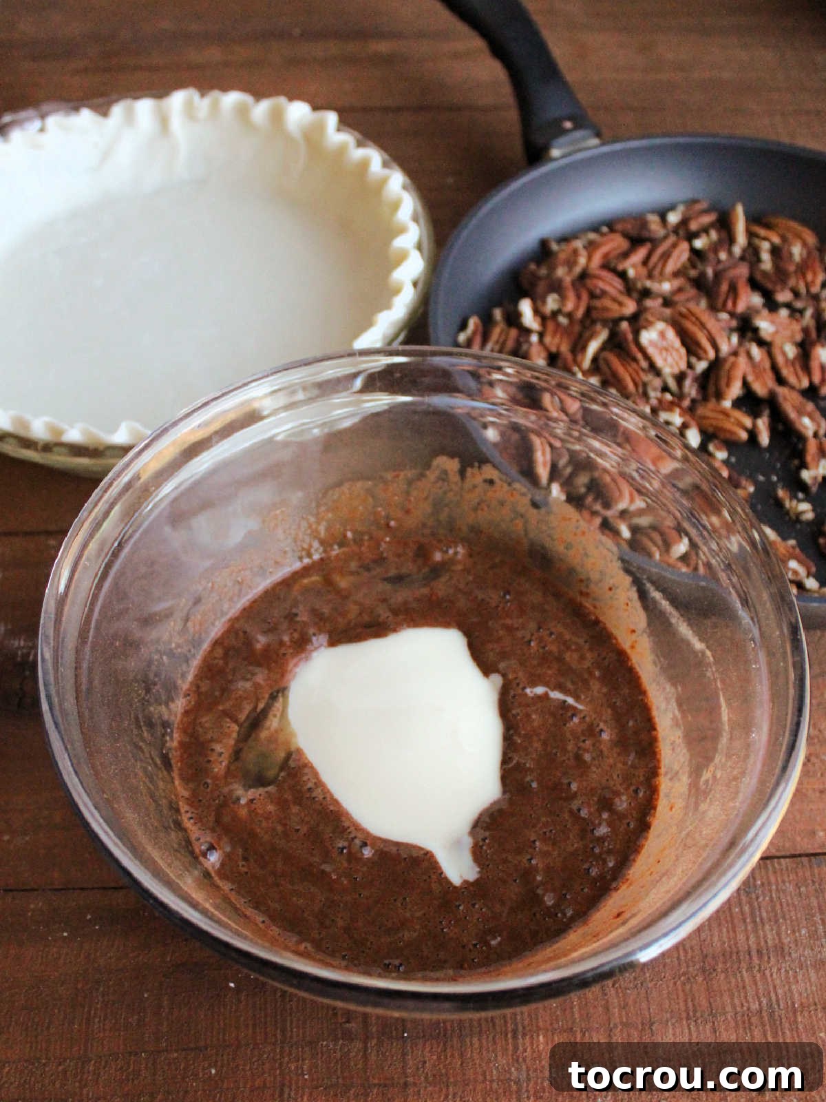 Large mixing bowl with condensed milk poured into chocolate egg mixture, ready to be made into pecanpie filling.