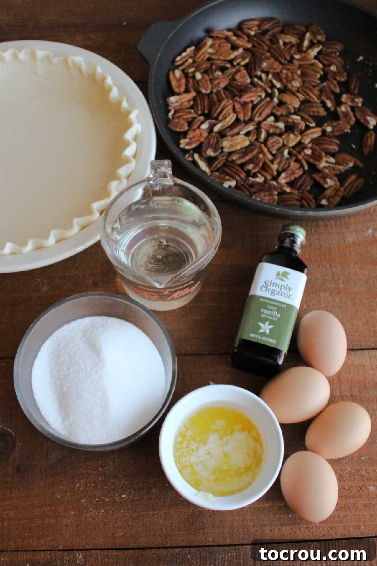 Timeless Pecan Perfection 3 Ingredients including pie crust, toasted pecans, vanilla, eggs, melted butter, sugar, and corn syrup ready to be made into classic pecan pie.