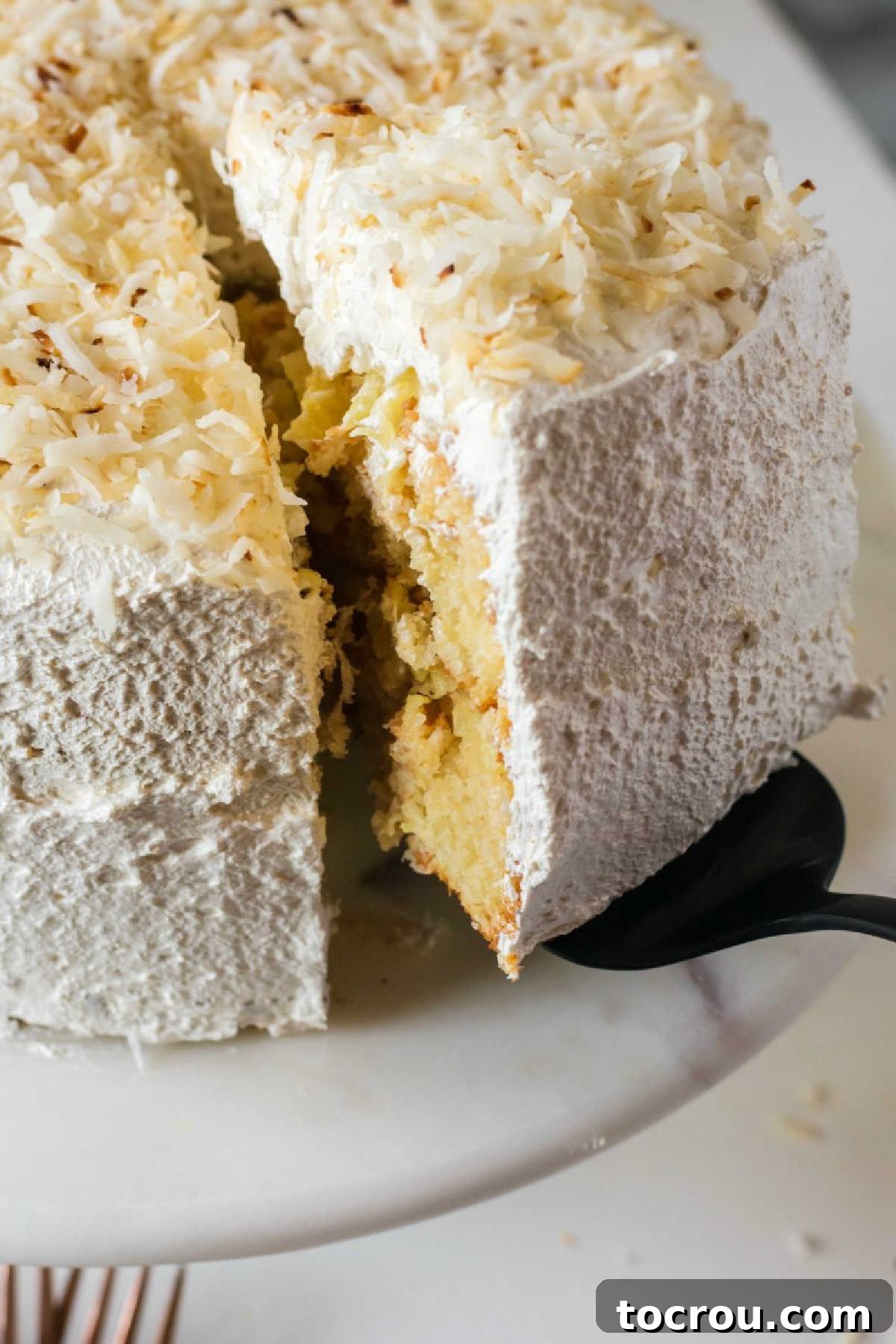 The tantalizing first slice of Haleakala cake, showcasing the luscious pineapple filling cascading out from between the tender white cake layers.