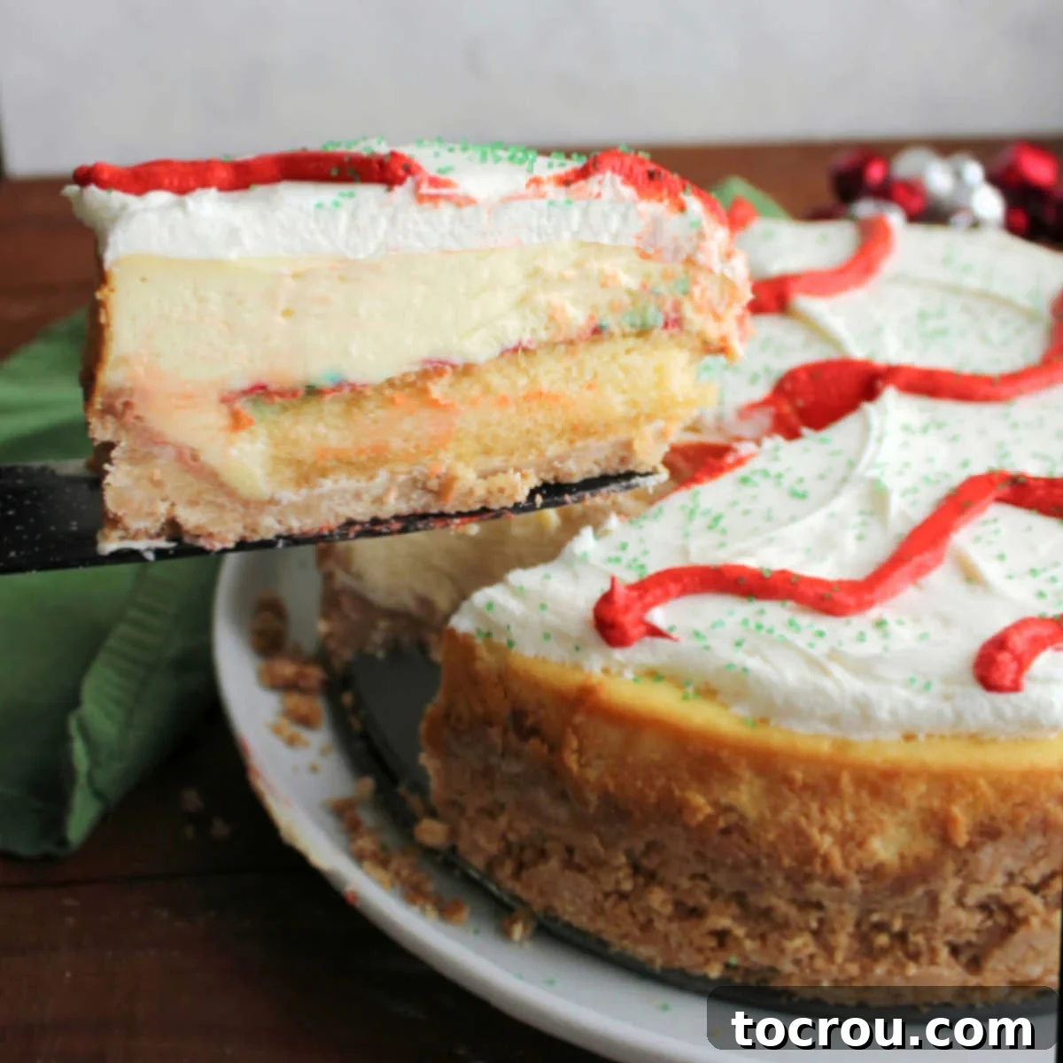 Lifting first slice of Little Debbie Christmas tree cheesecake out showing layer of crust topped with cake, then cheesecake and marshmallow buttercream for layers of festive goodness.
