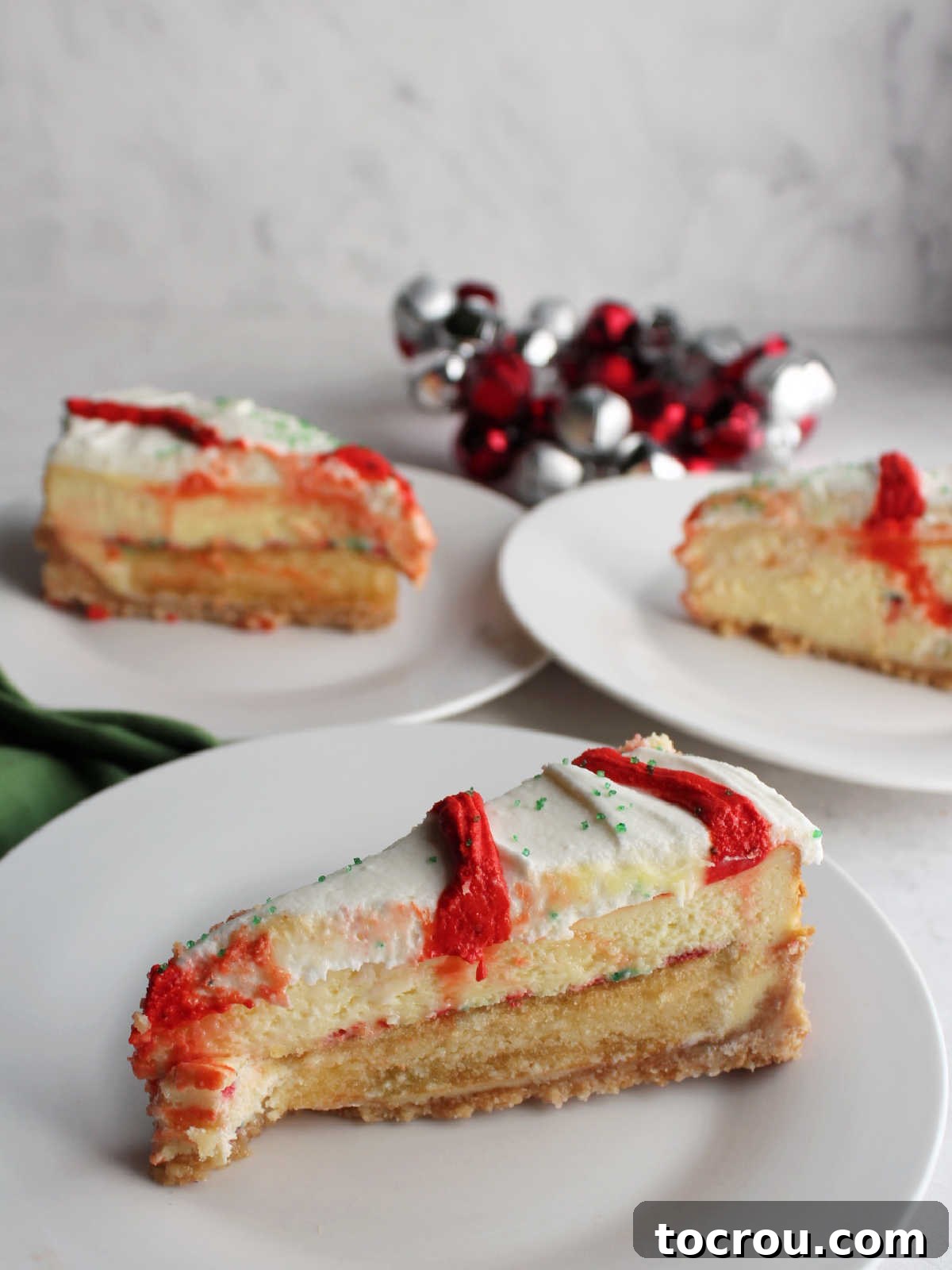 Three slices of Little Debbie christmas tree cheesecake served on small plates showing the layers of crust, cake, cheesecake, and frosting.
