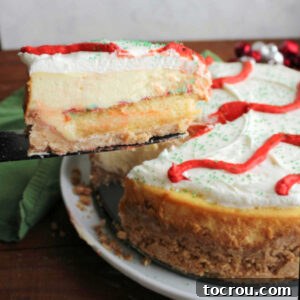 Lifting first slice of Little Debbie Christmas tree cheesecake out showing layer of crust topped with cake, then cheesecake and marshmallow buttercream for layers of festive goodness.