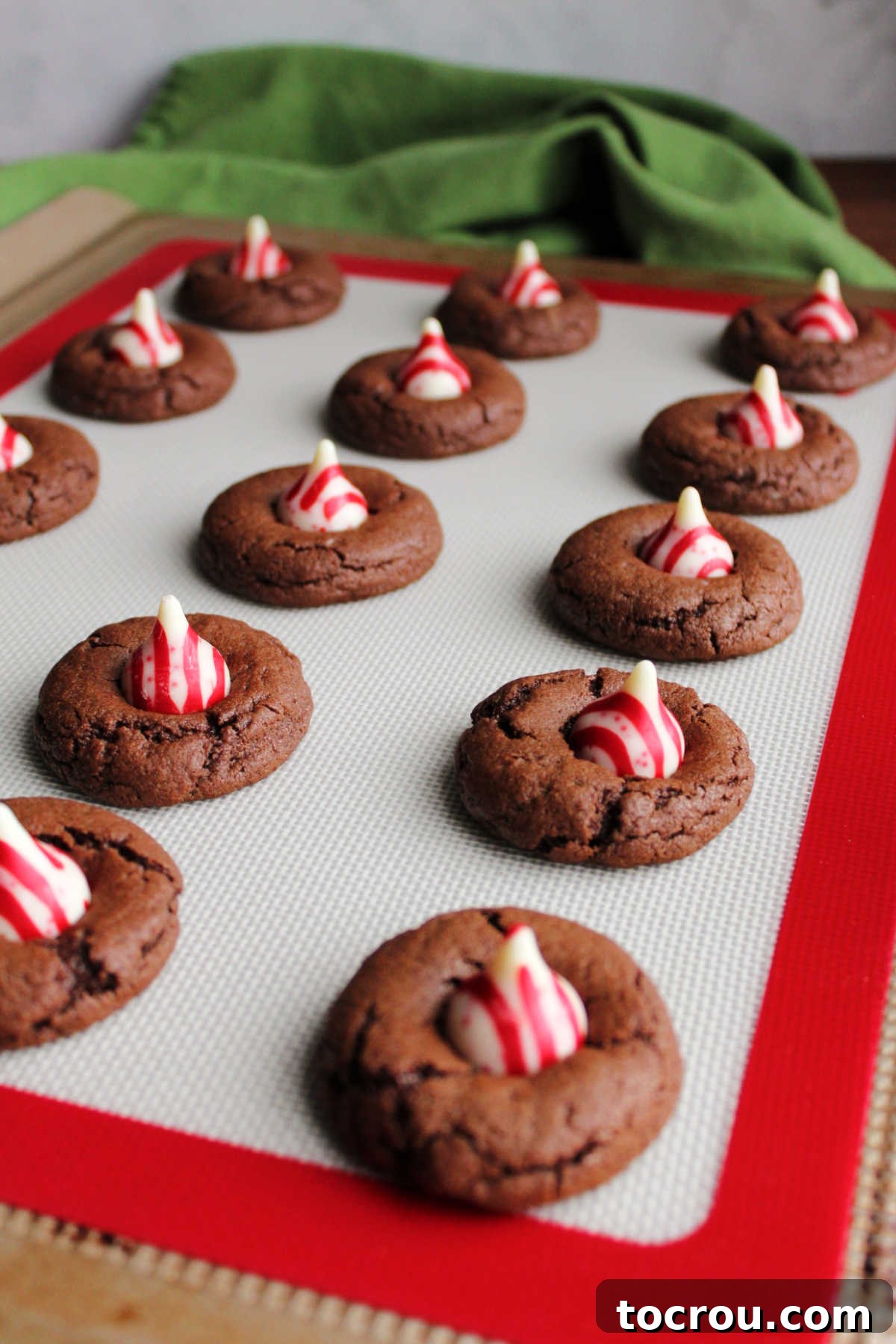 Peppermint Kissed Chocolate Blooms 8 Red and white striped candy cane Hershey's Kisses being pressed gently into warm chocolate cookies, creating the iconic blossom shape.