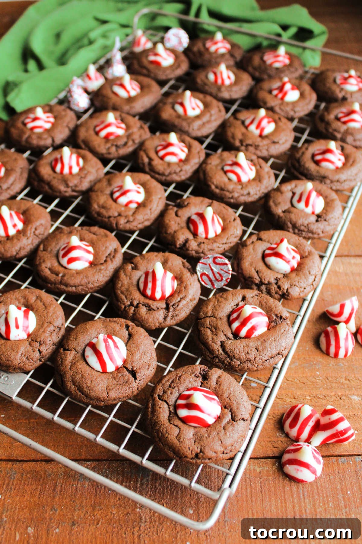 Peppermint Kissed Chocolate Blooms 9 Cooling rack filled with an array of chocolate peppermint blossom cookies, each topped with a vibrant candy cane Kiss.