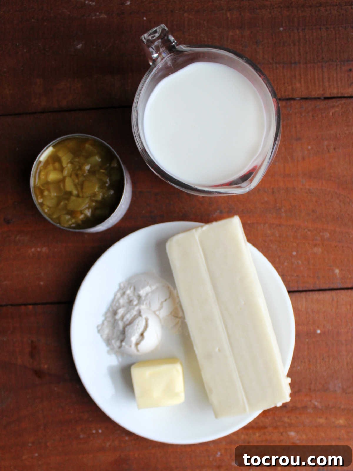 Ingredients including butter, flour, milk, a block of Monterey Jack cheese and a can of green chilies ready to be made into a cheese sauce for the enchiladas.
