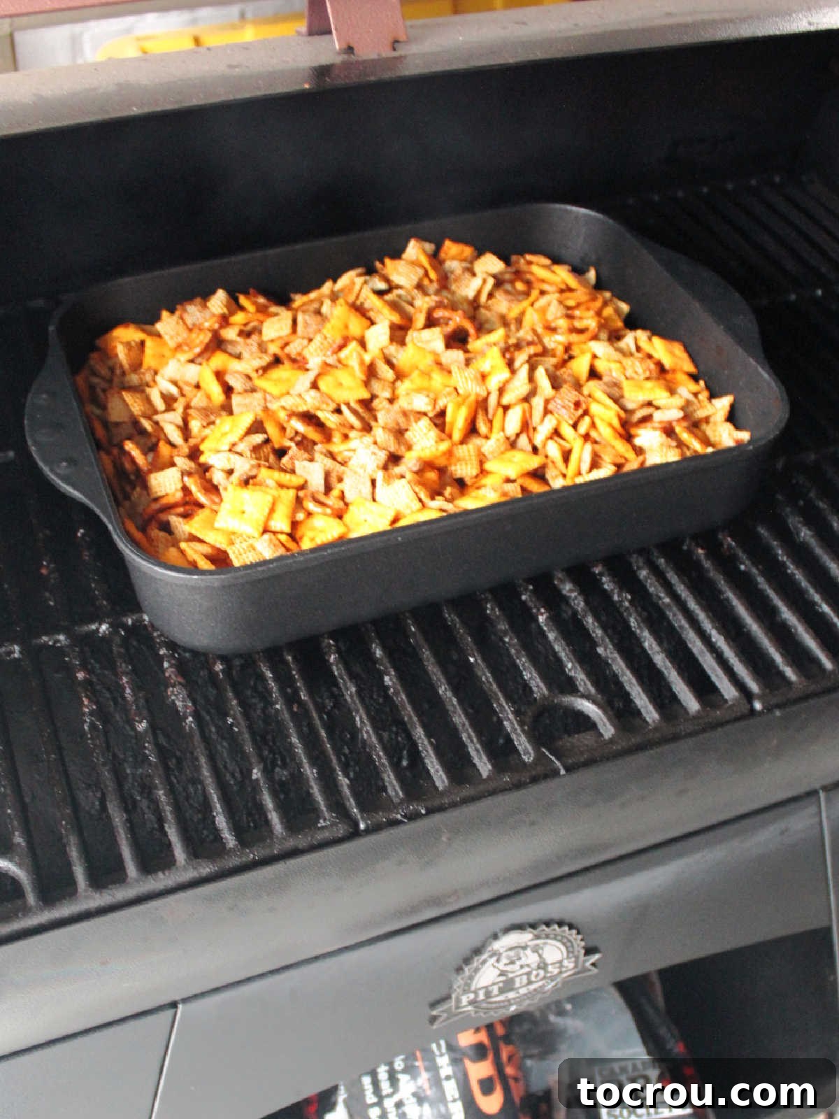 Roasting pan of BBQ Chex mix on Pit Boss Smoker.