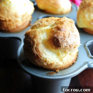 Freshly baked golden brown popover ballooning above a popover pan.