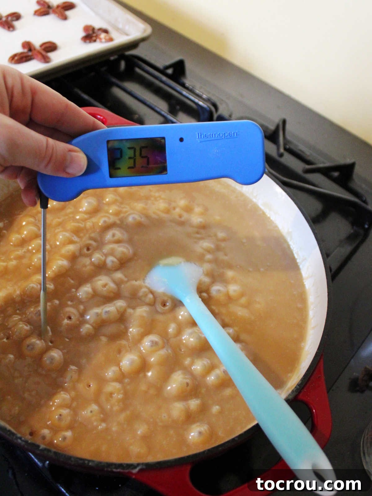 Pan of boiling caramel mixture with instant read thermometer reading 235 degrees Fahrenheit. 