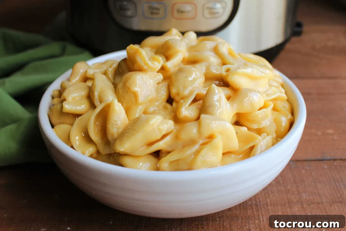 White serving bowl piled high with creamy shells and cheese in front of an Instant Pot. 