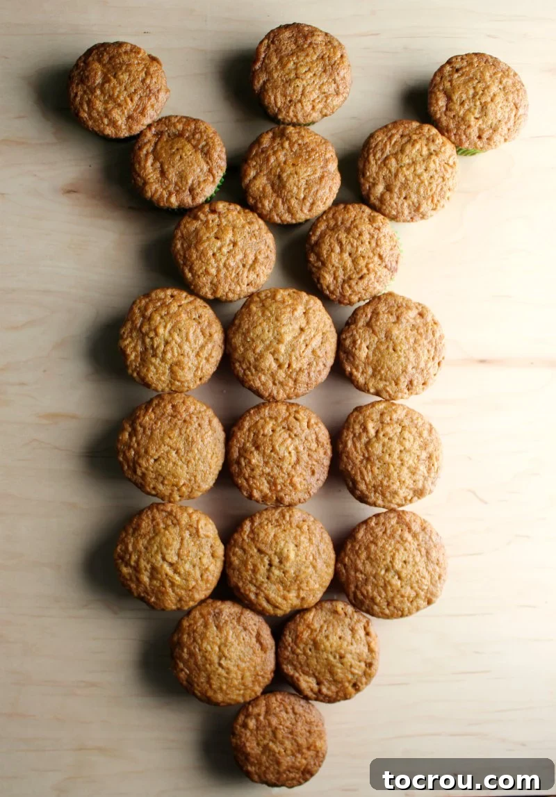Pull-Apart Carrot Cake: A Cupcake Masterpiece 3 Cupcakes arranged precisely on a platter in the distinct shape of a carrot, forming the base before frosting is applied. The arrangement includes orange-lined cupcakes for the carrot body and green-lined cupcakes for the fronds.