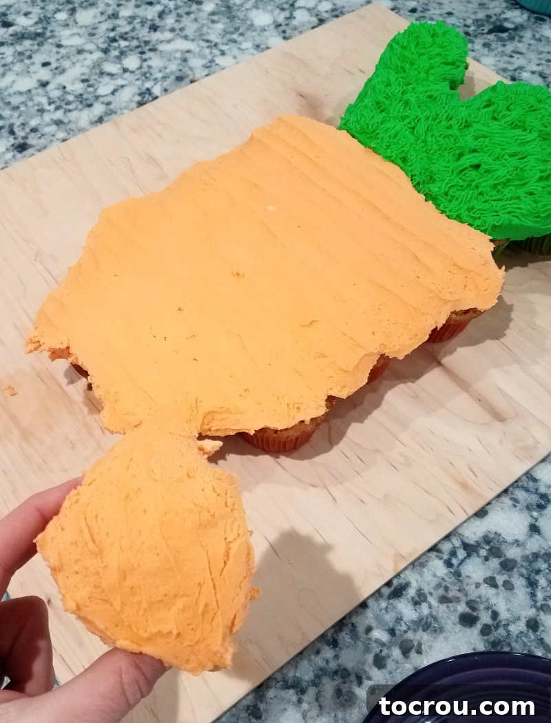 Pull-Apart Carrot Cake: A Cupcake Masterpiece 9 A hand reaches in to pull off an orange-frosted cupcake from the end of the meticulously decorated carrot-shaped pull-apart cake, showcasing the ease and enjoyment of serving this unique dessert.