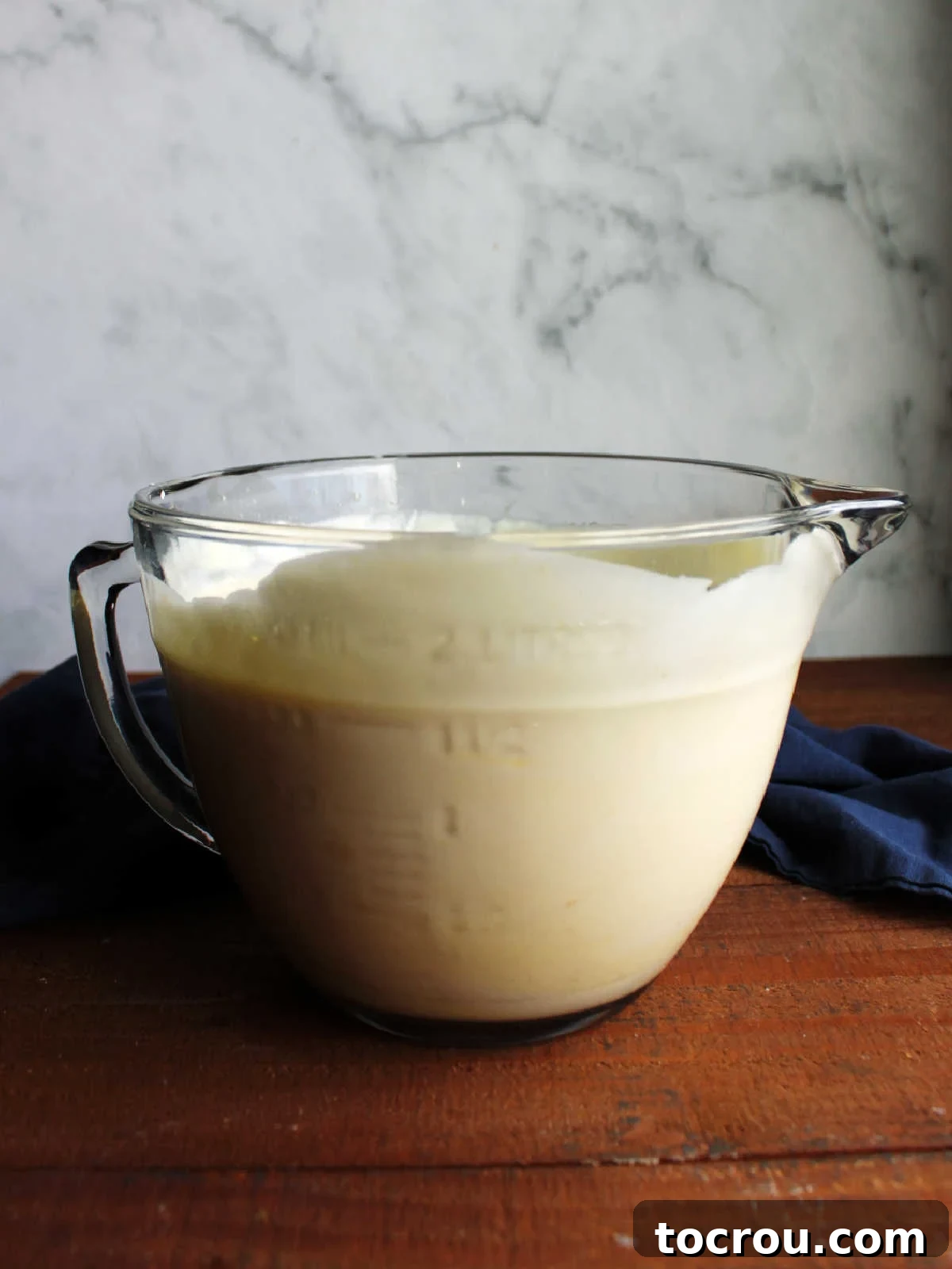 Pudding and Cool Whip Mixture A clear glass batter bowl brimming with a light and fluffy mixture of vanilla pudding and whipped topping, perfectly blended and ready for layering.