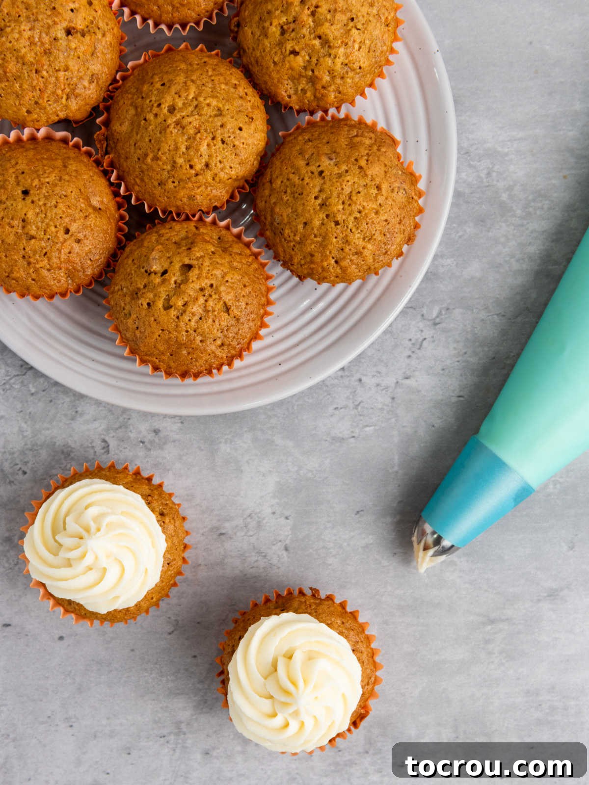Rustic Carrot Cake Cupcakes 8 Piping bag of frosting making swirls of frosting on carrot cupcakes.