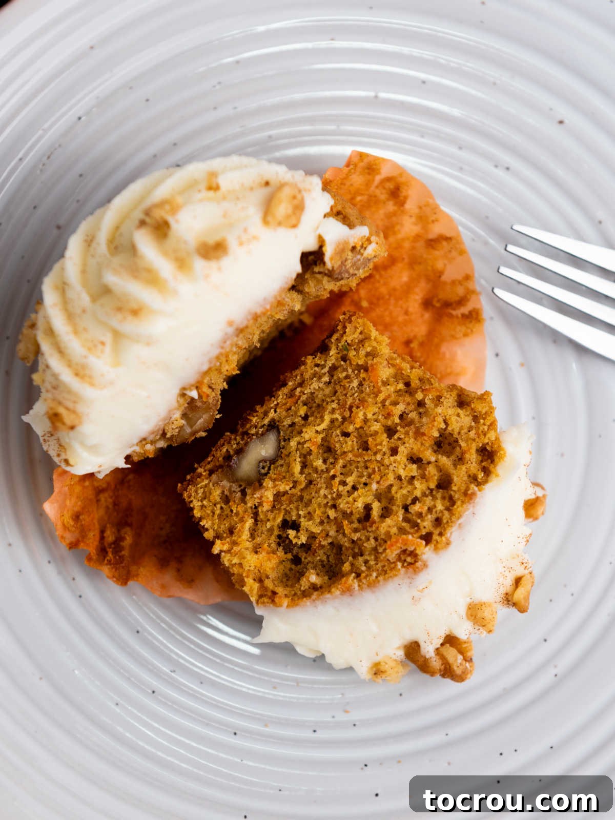 Rustic Carrot Cake Cupcakes 9 Carrot cupcake cut in half showing soft interior with buts of chopped nuts inside.