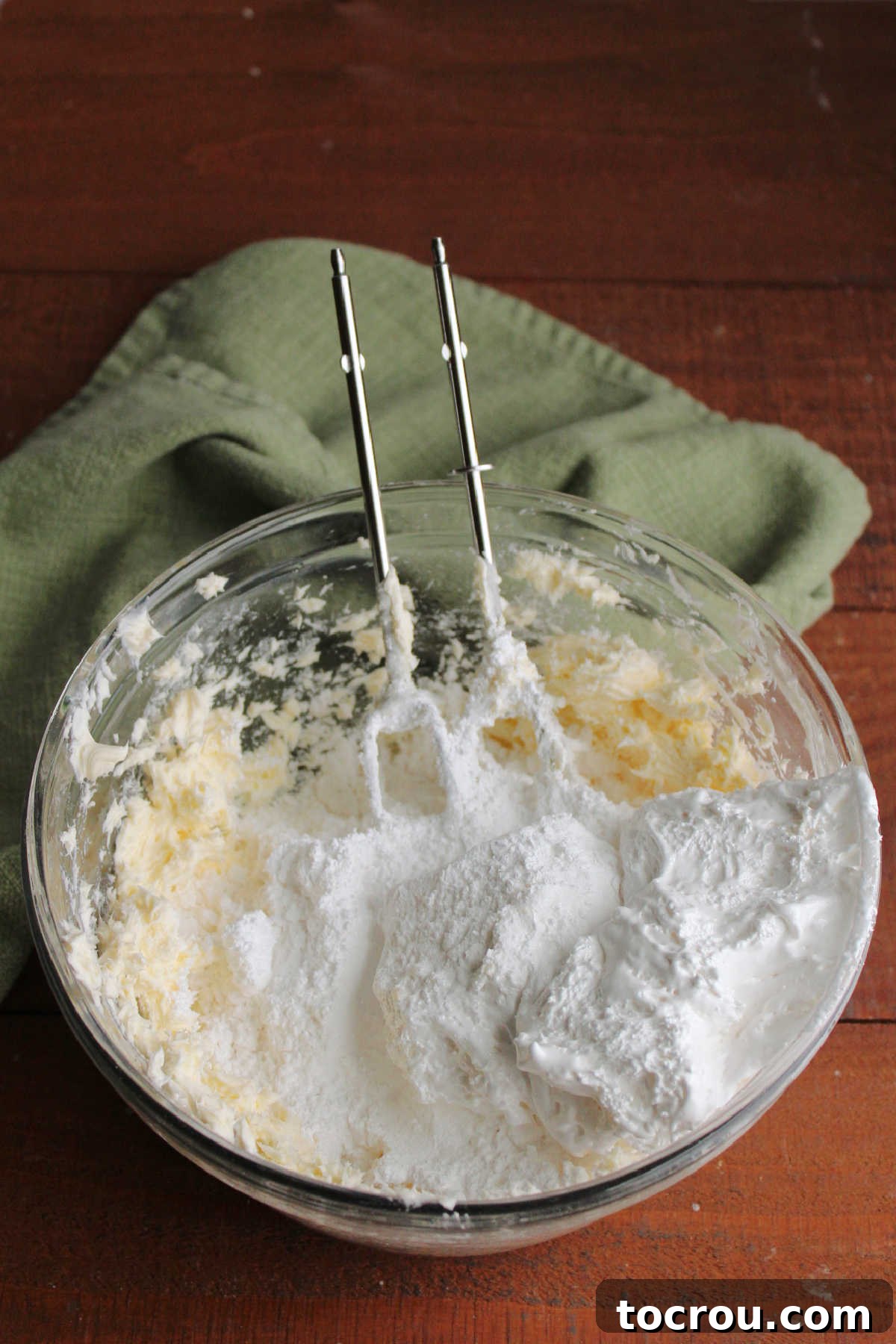 Adding powdered sugar and marshmallow fluff to bowl of creamed butter.