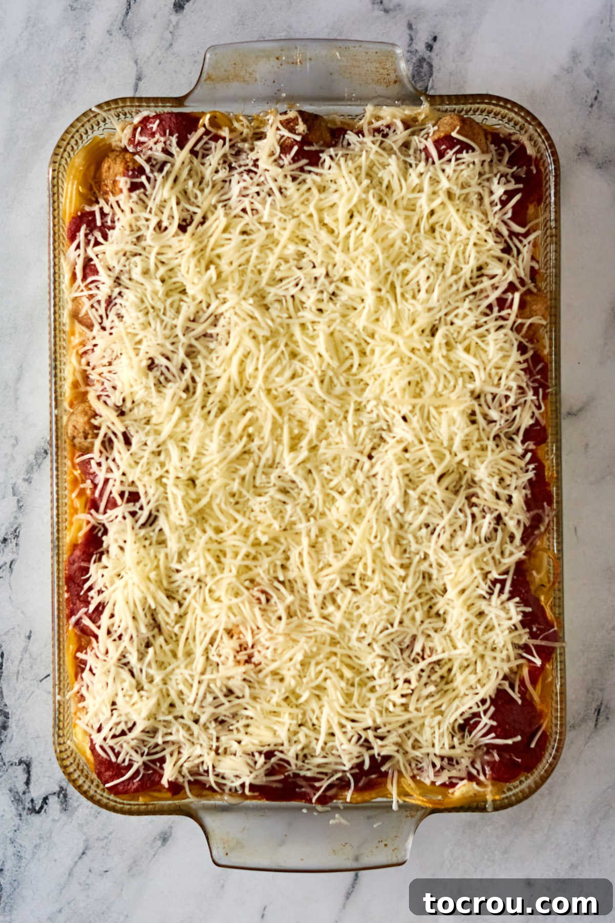 Baked spaghetti and meatballs topped with melty cheese, ready to serve.