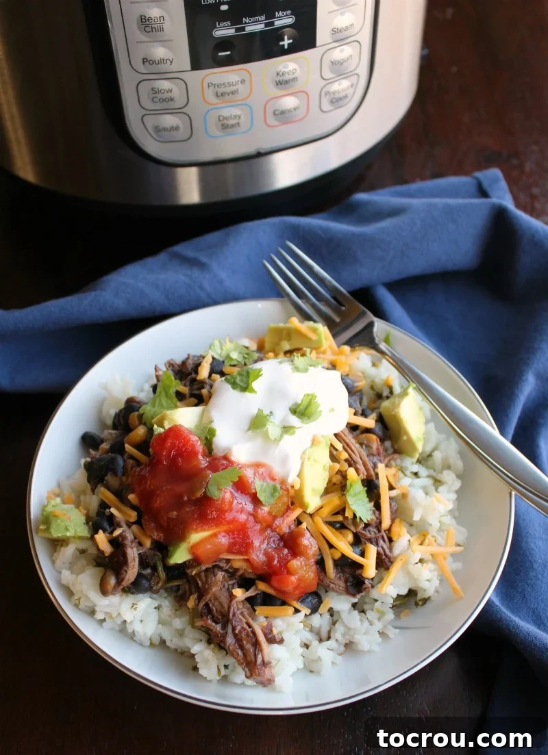 Rice bowl topped with salsa chicken, salsa, cheese, and sour cream in front of Instant Pot.