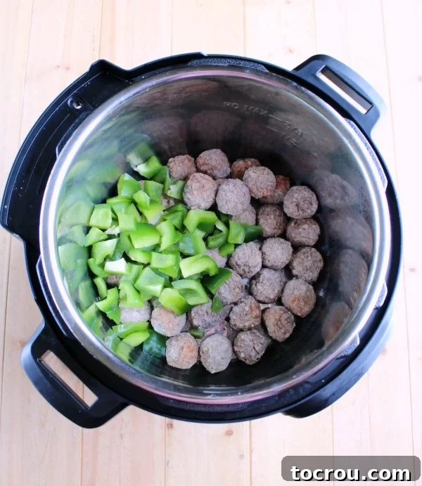 Instant Pot Swiss Steak Inspired Meatballs 3 frozen meatballs and green peppers in instant pot.