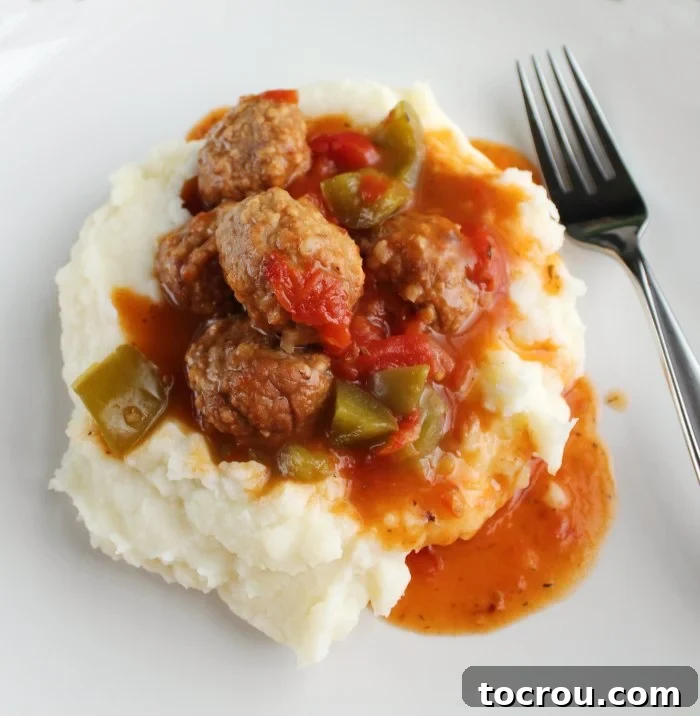 Instant Pot Swiss Steak Inspired Meatballs 5 close pile of mashed potatoes topped with meatballs in tomato sauce with big pieces of bell pepper.