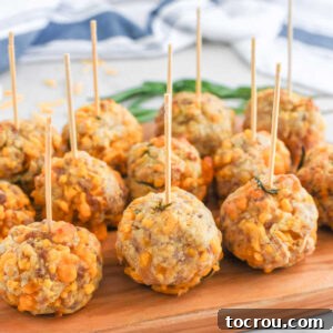 Sausage Cheese Bites 11 Sausage balls arranged on a wooden platter with toothpicks for easy serving showing the small balls with lots of cheddar cheese and some rosemary inside.