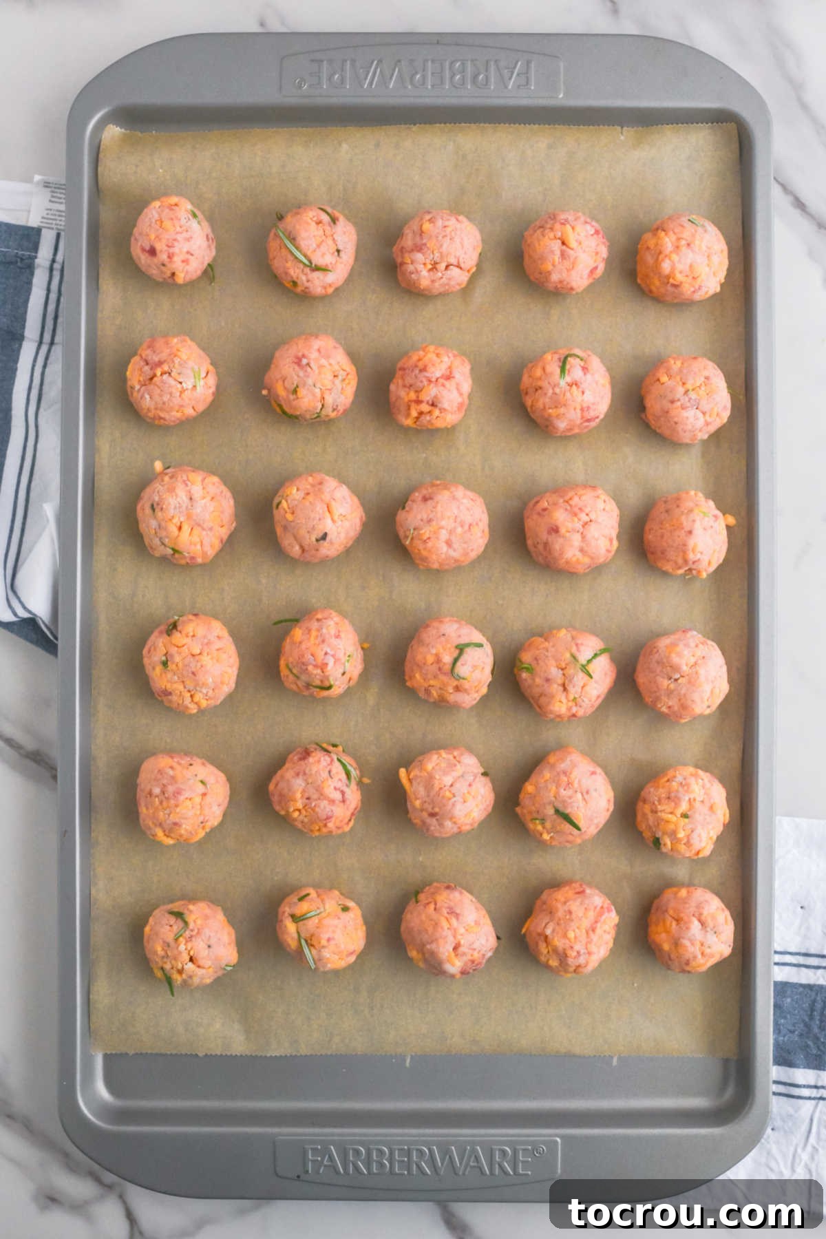 Sausage Cheese Bites 8 Baking sheet of round balls of sausage mixture arranged over parchment paper, ready to go in the oven.