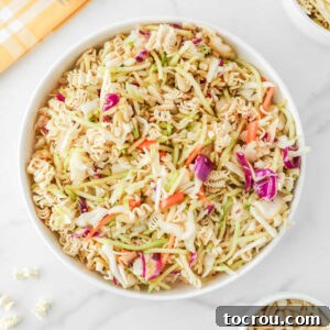 Serving bowl of ramen noodle coleslaw with cabbage, broccoli, carrots, almonds, and bits of crunchy ramen noodles all in a light soy sauce vinaigrette.