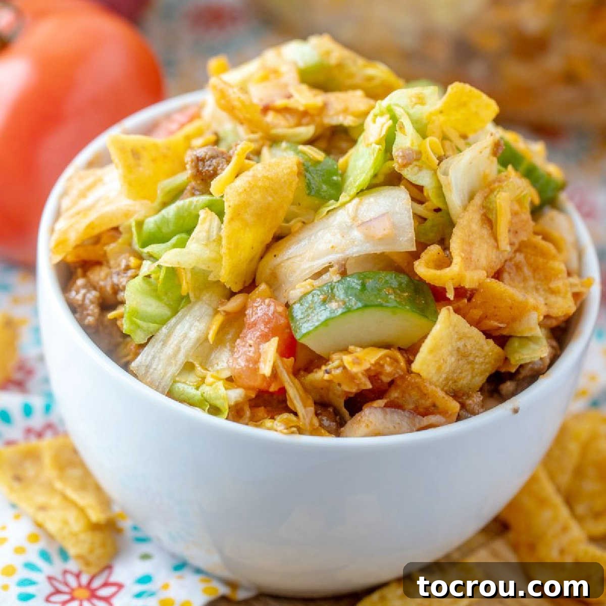 Frito Salad: A fun, flavorful twist on taco salad, perfect for potlucks and family dinners, featuring easy homemade Catalina dressing and packed with wholesome ingredients. A vibrant close-up of a bowl of Frito Taco Salad, showcasing crisp lettuce, fresh cucumbers, shredded cheese, seasoned taco meat, and crunchy Fritos, all coated in a rich homemade Catalina dressing.