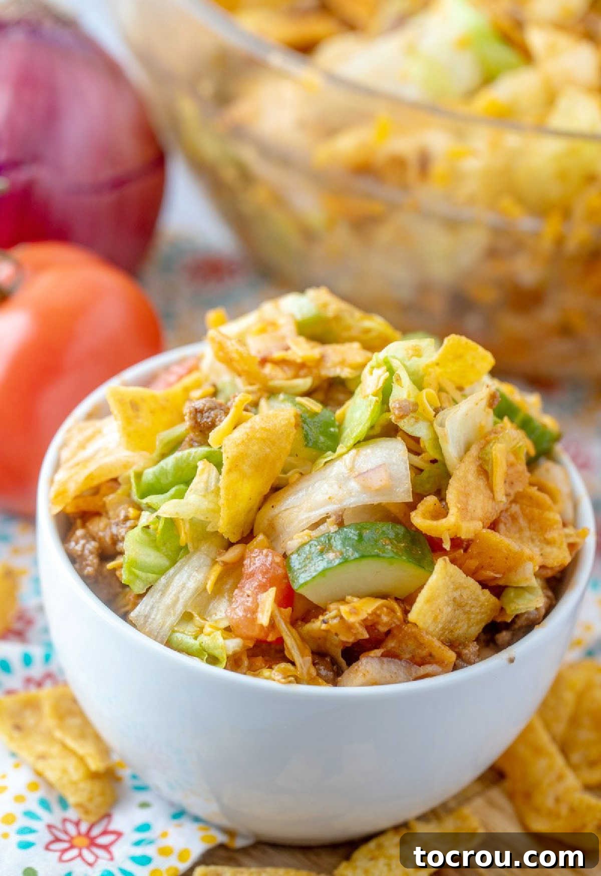 Frito Taco Salad: Perfect for individual servings or large gatherings. A small individual bowl of Frito Taco Salad placed in front of a larger serving bowl, ready for a gathering.