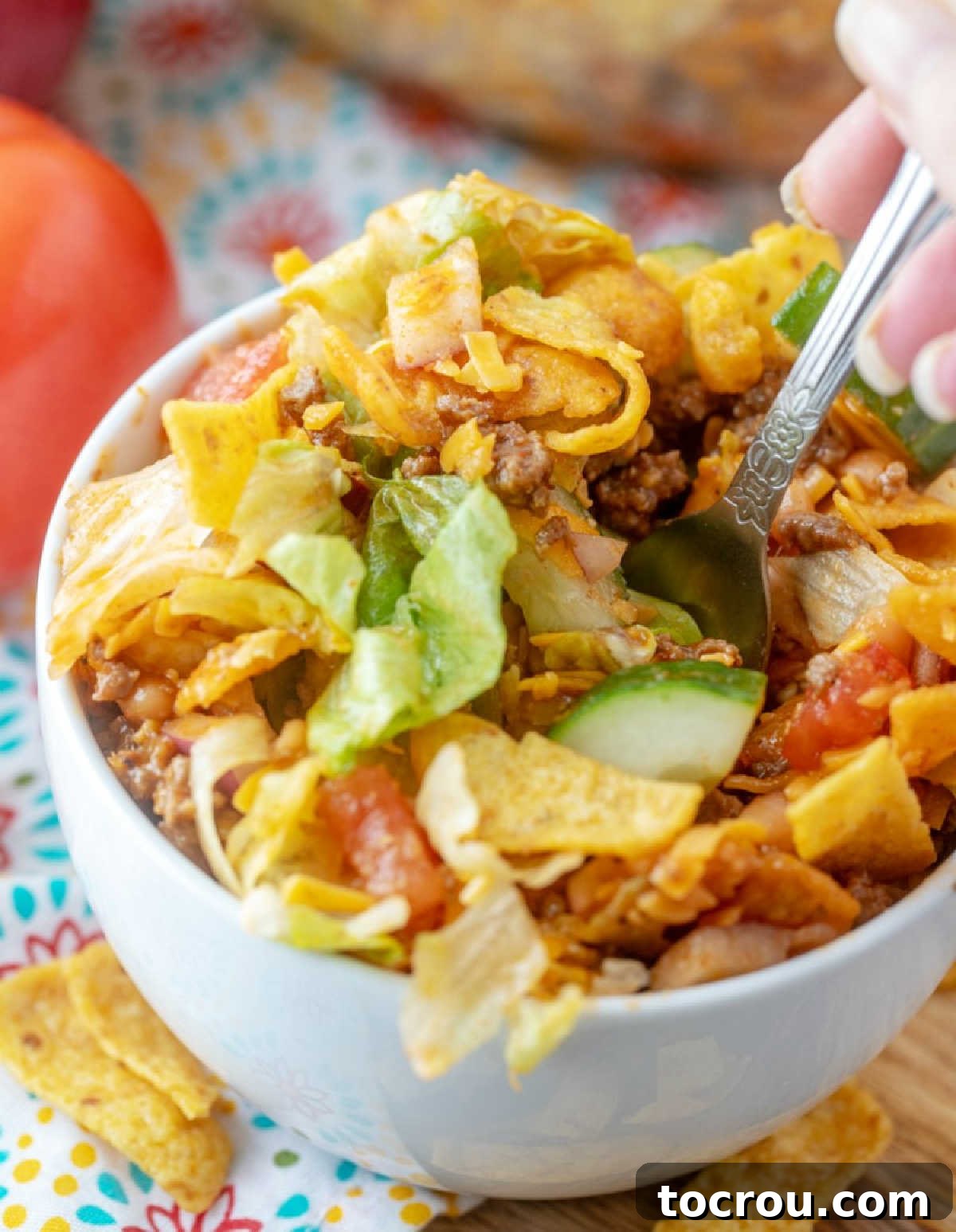 Enjoying a bite of Frito Taco Salad. A fork taking a delightful bite of Frito Taco Salad, showcasing the layers of fresh ingredients.
