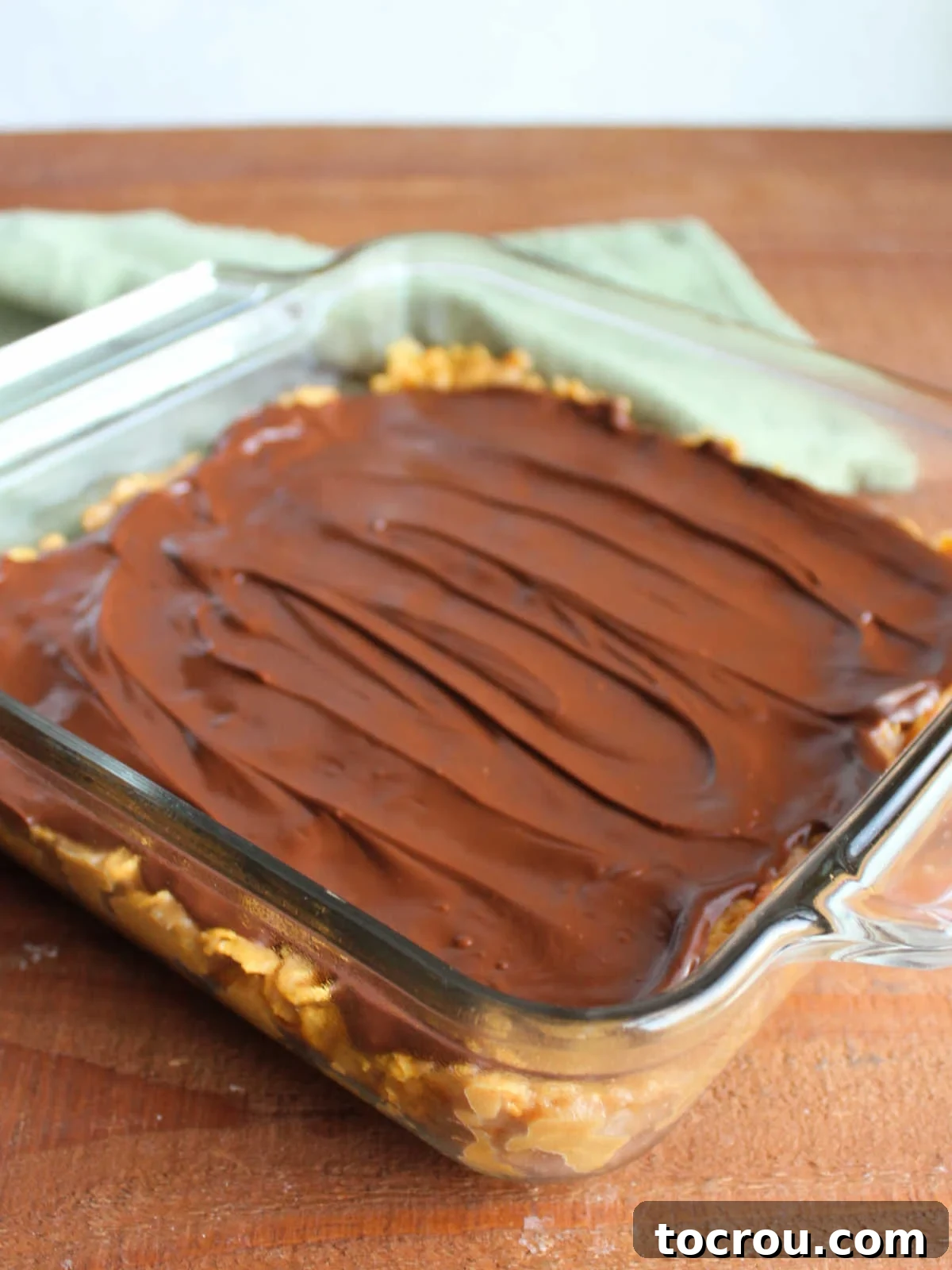 The finished masterpiece, chilling to perfection. Pan of finished peanut butter cornflake bars, topped with a smooth chocolate peanut butter layer, ready to be cut into squares.