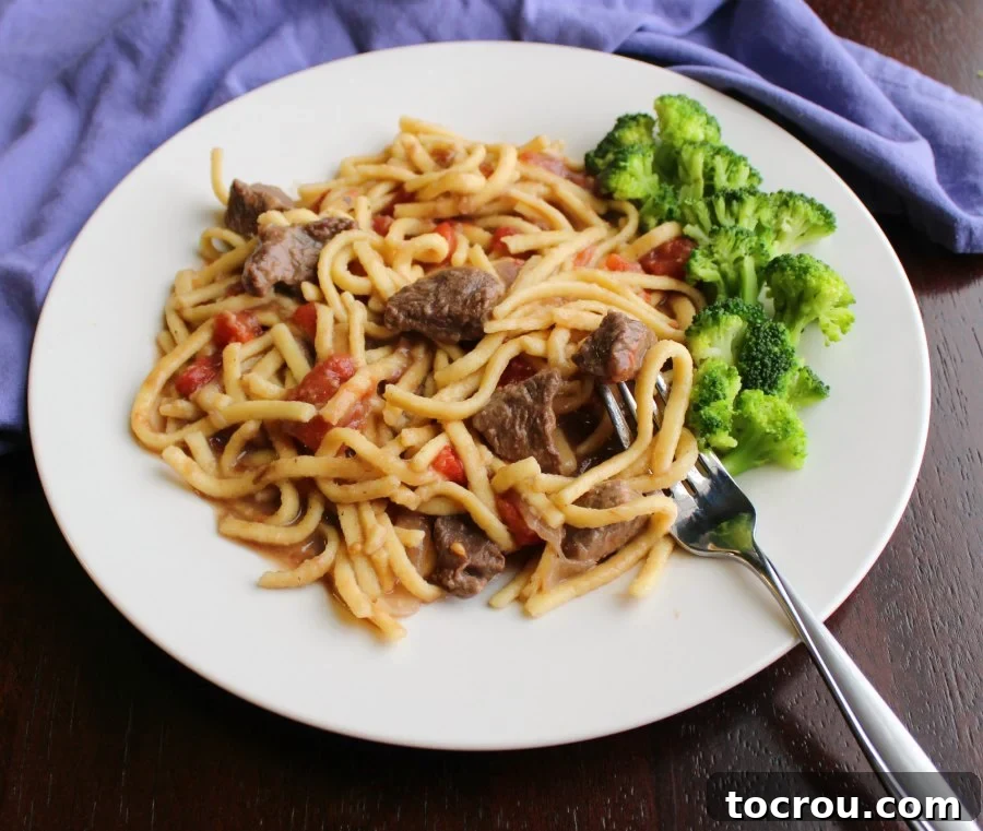 A perfectly portioned plate of Cavanaugh's Beef and Noodles with Tomatoes, accompanied by a side of steamed broccoli, ready for a delicious meal.