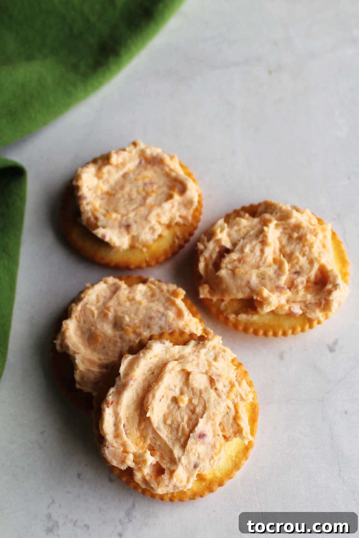 Crackers topped with bacon cheddar ranch cheese ball spread ready to eat.