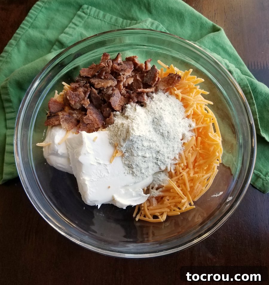 bowl filled with cream cheese, ranch seasoning, cheese and bacon.