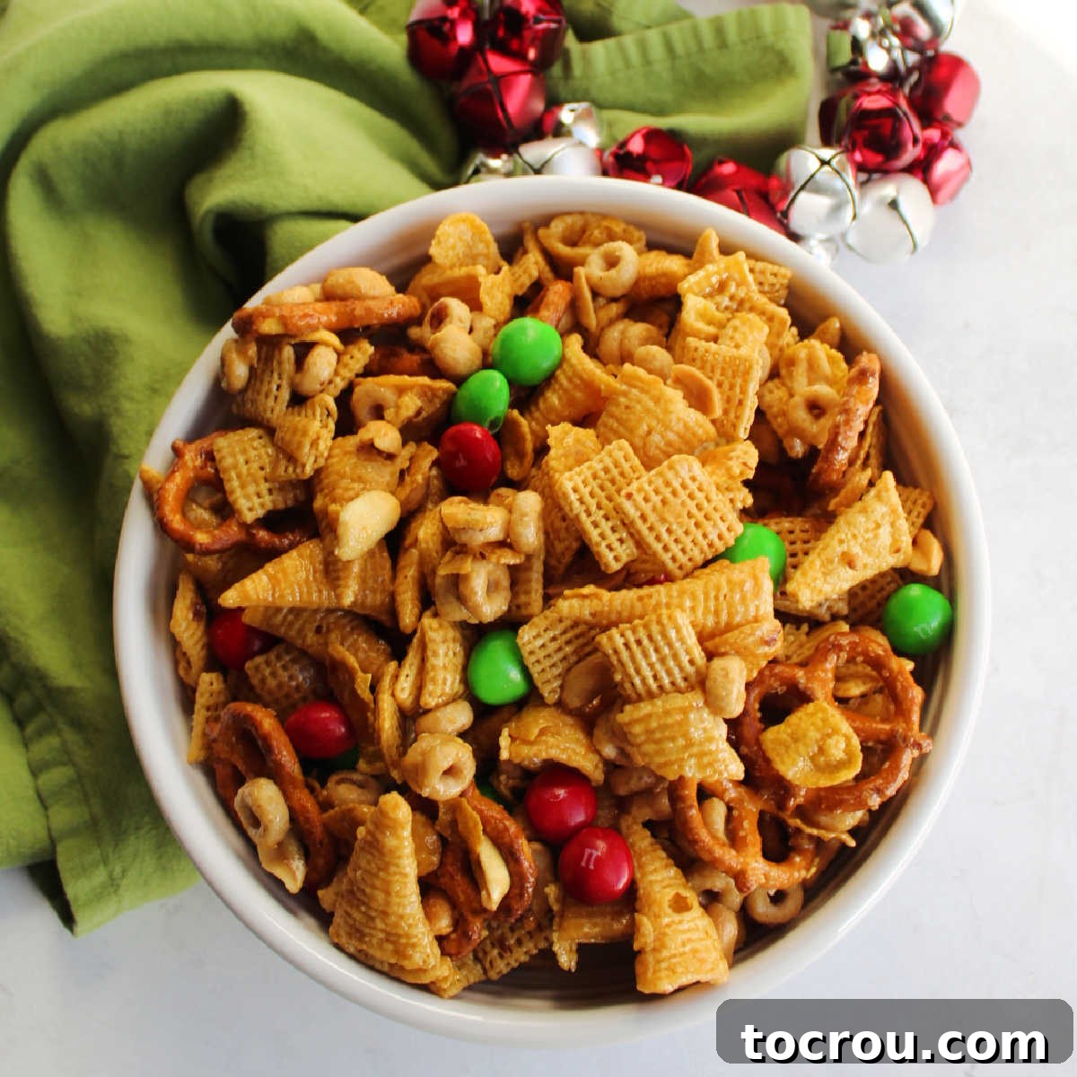 Bowl of caramel snack mix with bugles, pretzels, peanuts, Chex, corn flakes, M&Ms and more, ready to eat.