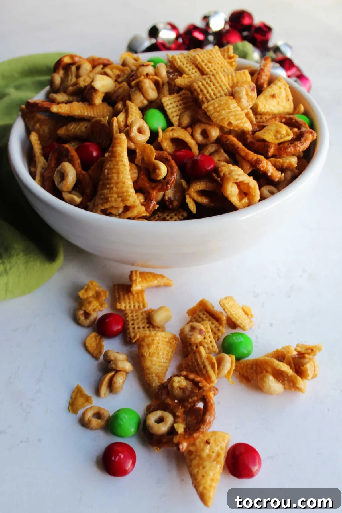 Bowl of crunchy caramel bugle mix with pretzels, cereal, peanuts and red and green M&M's ready to eat.