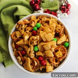 Bowl of caramel snack mix with bugles, pretzels, peanuts, Chex, corn flakes, M&Ms and more, ready to eat.
