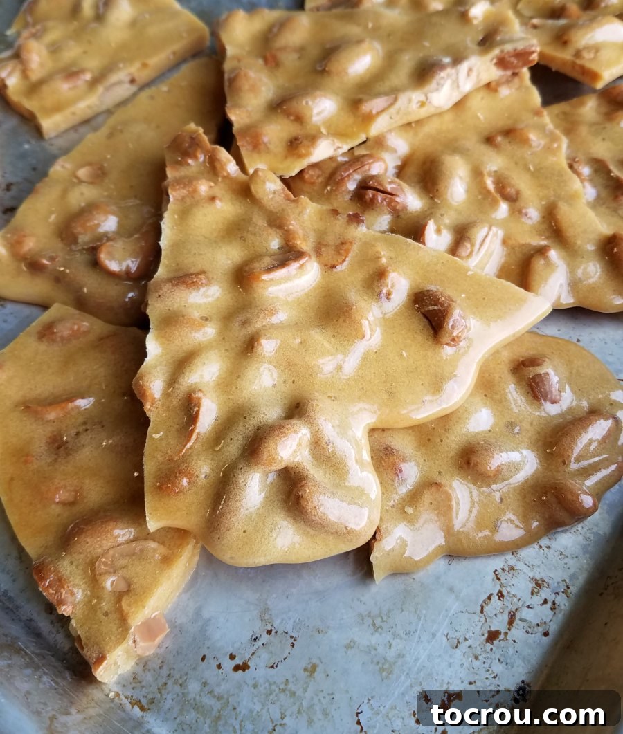 Chunks of perfectly broken up peanut brittle on a baking sheet, ready for serving or storage.