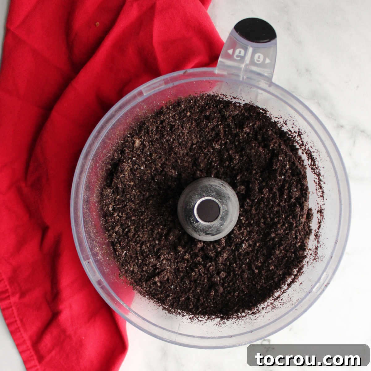 Crushed Oreo cookie crumbs in a food processor, forming the base for the cheesecake crust.