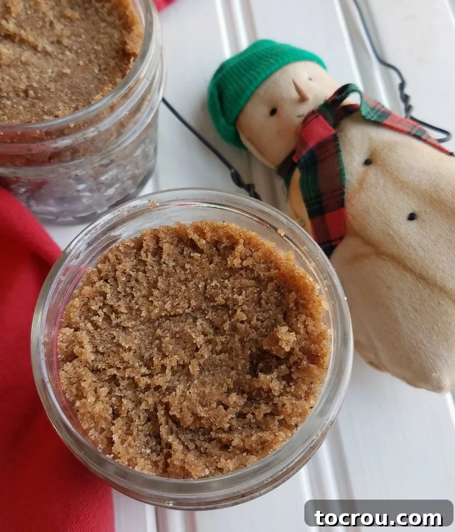 Jars of homemade snickerdoodle brown sugar scrub with a snowman decoration nearby.