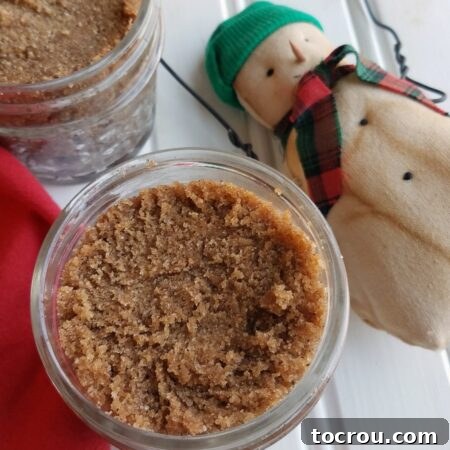 Jars of homemade snickerdoodle brown sugar scrub with a snowman decoration nearby.