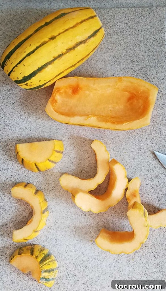 Delicata squash cut in half and then into crescent shaped slices, showing the edible skin.