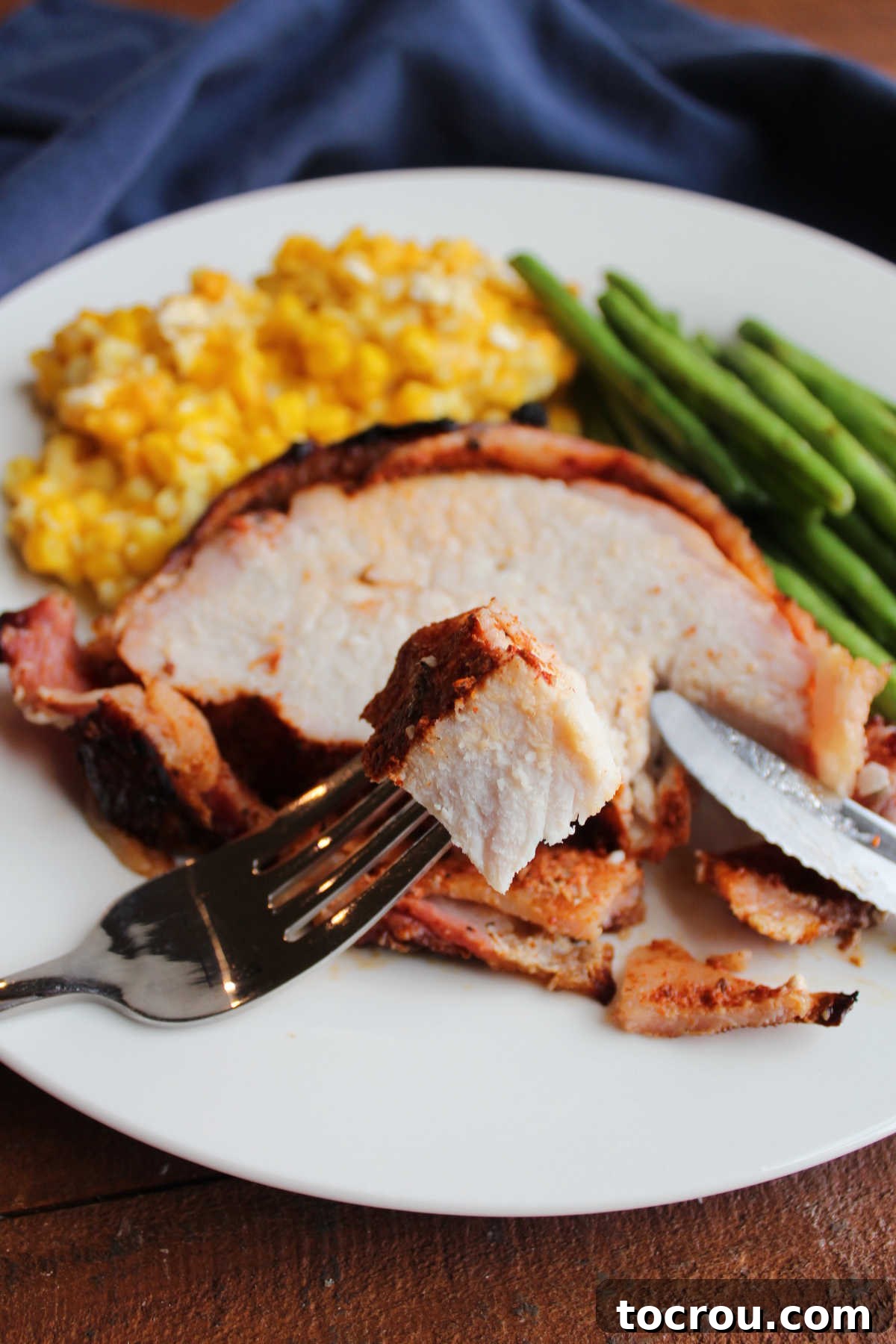 Bite of tender, juicy smoked pork loin on fork, ready to enjoy.